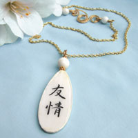 white and black lacquered paper necklace with the Japanese kanji that says Friendship