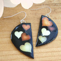 black earrings with tan, light gray, and white hearts